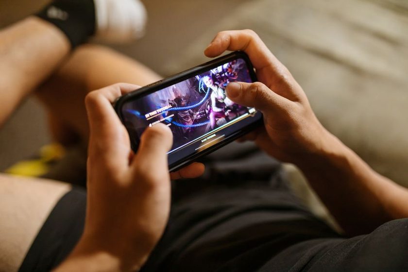 Pessoa jogando em um celular segurando com as duas mãos